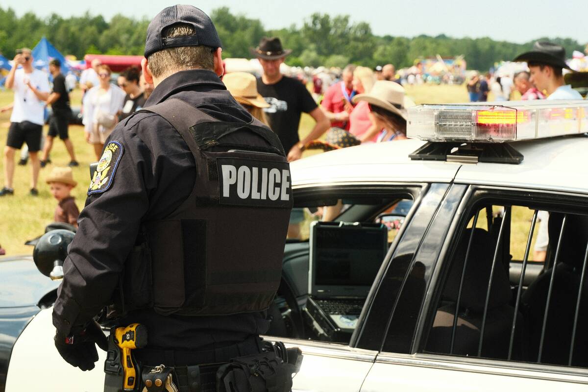 A police officer standing beside a patrol car at an outdoor event