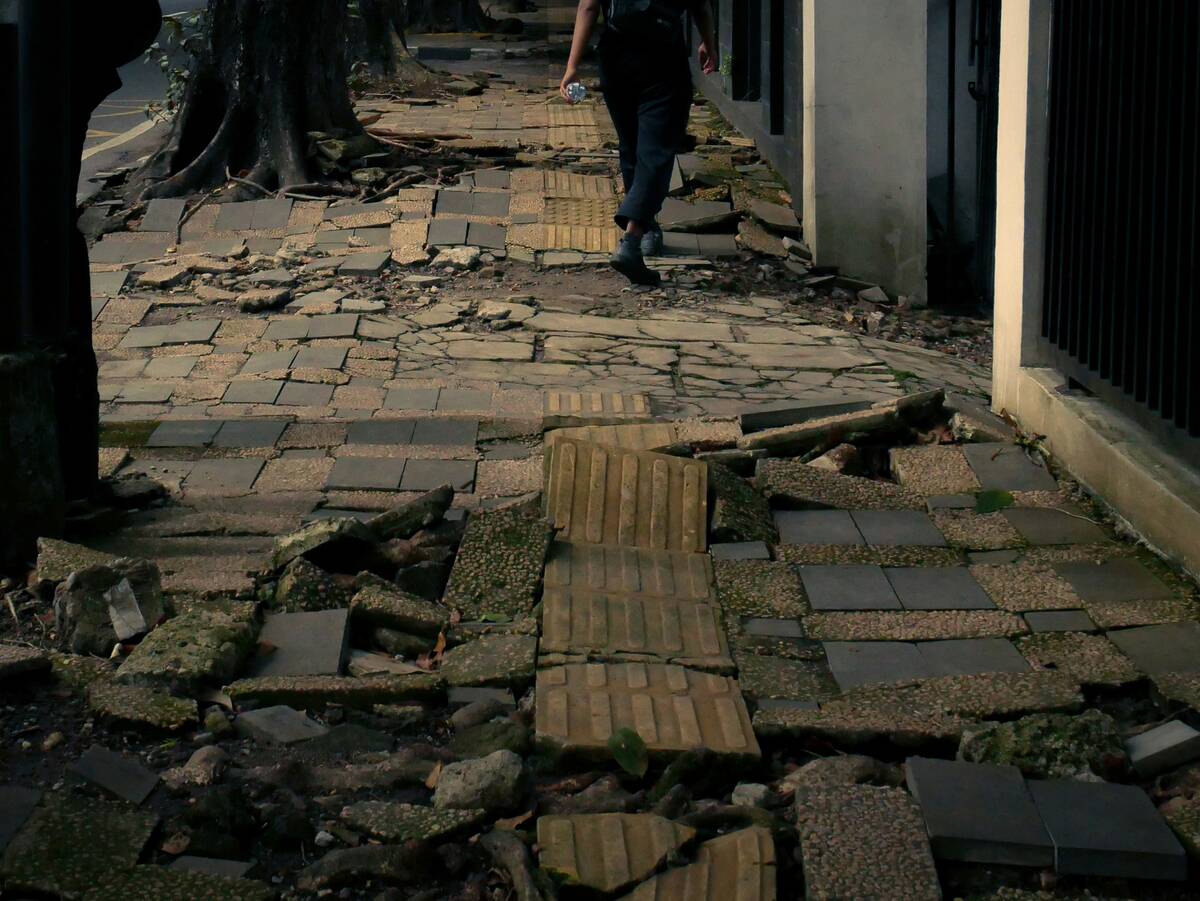 A person walking on a broken, uneven brick sidewalk