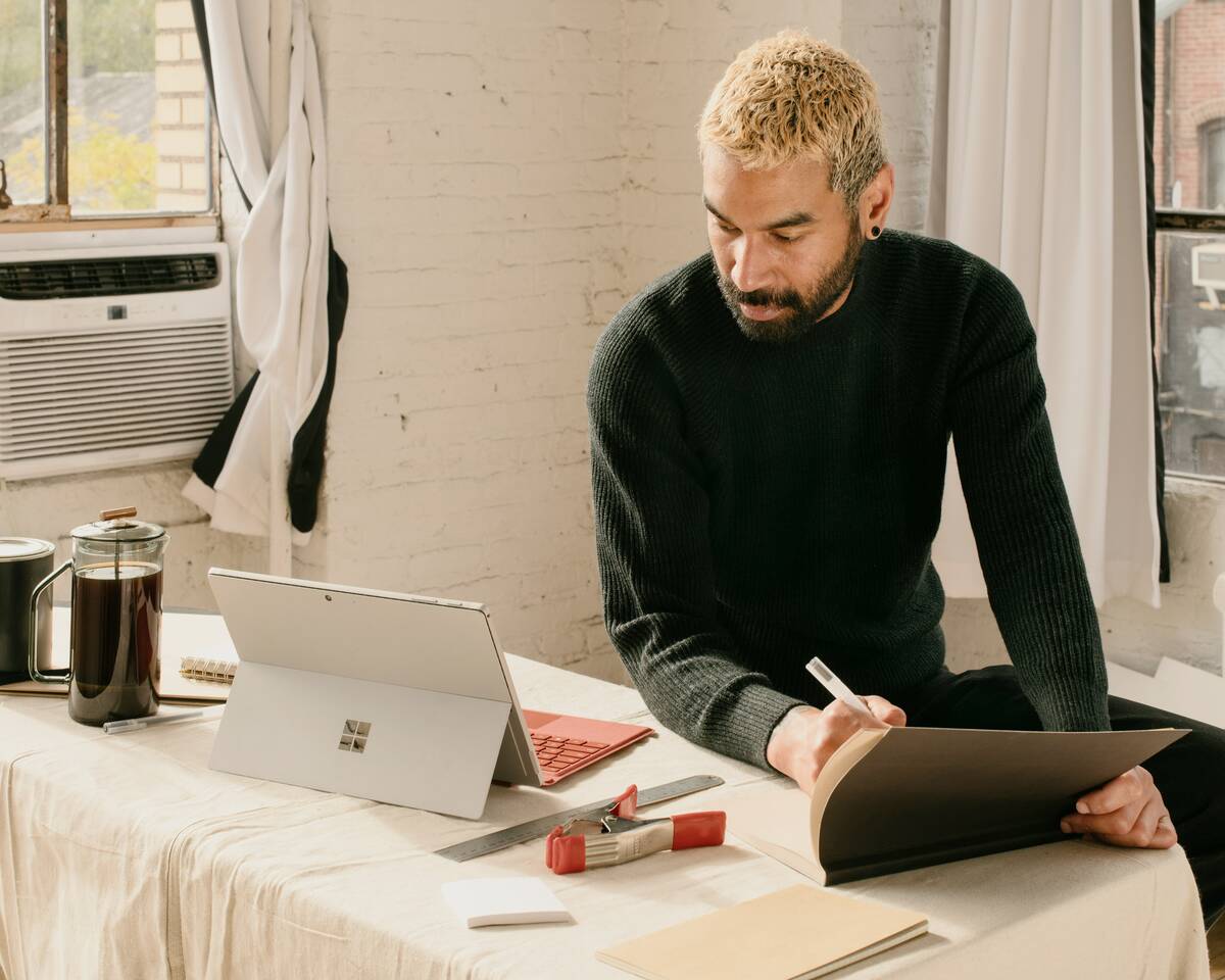A man sitting at a table with a laptop and notebook